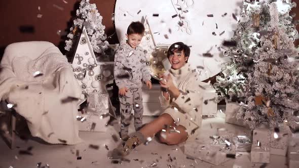 Playful Kid in Pyjamas and His Mother Under Confetti