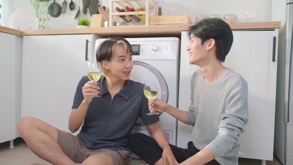 Asian handsome man gay family sit on floor drink cup of wine together to celebrate anniversary party alt