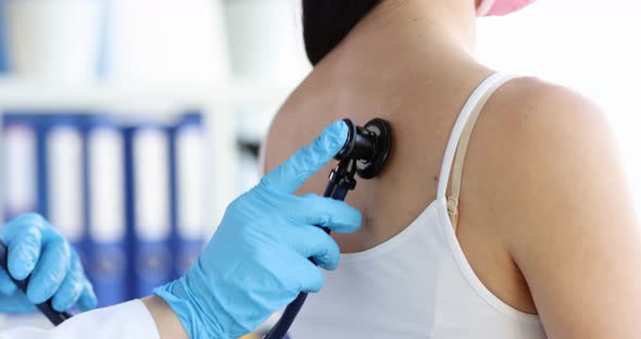 Doctor with Stethoscope Listens to Woman Breathing During Examination in Clinic alt