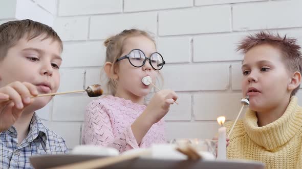 Three Interesting Cute Teenagers Roast and Eat Marshmallows on Candlesticks alt