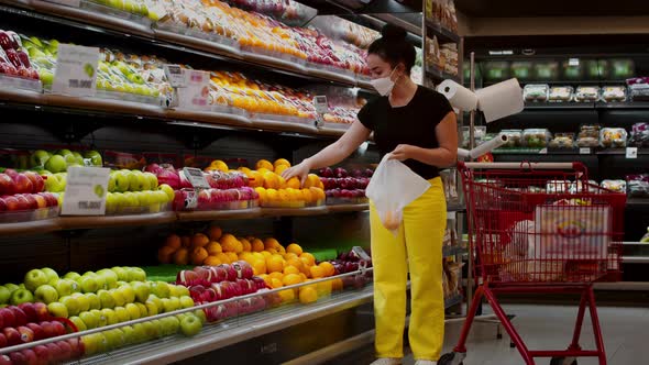 Young Woman in a Mask From a Coronavirus Epidemic is Standing in the Grocery Department of a alt