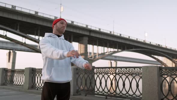 Young Man Stretching His Arm Muscles Under the Bridge Before Running. Handsome Athlete Male Doing alt