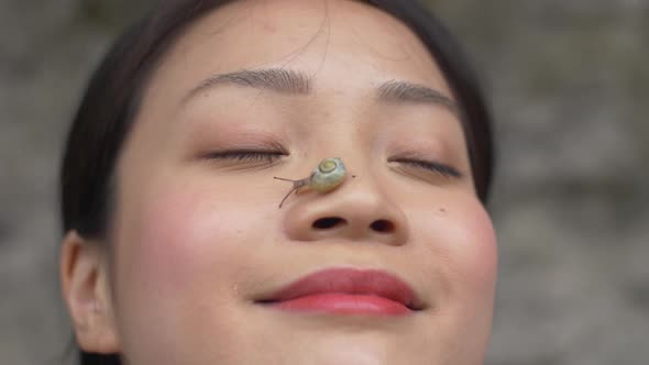 Serene woman with a snail on her nose