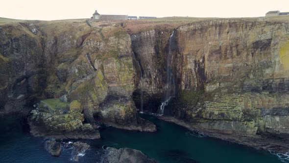 Drone shot of the cliffs and waterfall at Whaligoe in Scotland UK alt