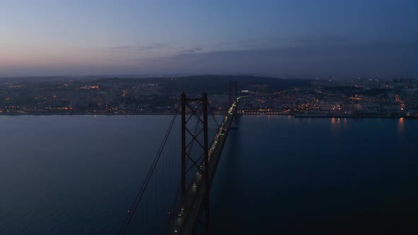 Aerial Night Orbit of Ponte 25 De Abril Red Bridge with Car Traffic and Lights Off the Coast of alt