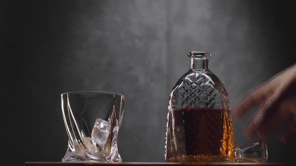 Whiskey Glass and Bottle on Table Against Dark Gray Background alt