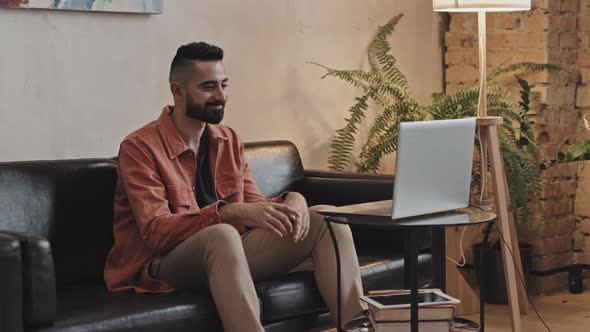 Man Sitting in Living Room and Chatting on Web Call on Laptop alt