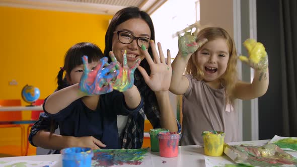 Kids and Teacher with Hands in Paint at Art Lesson alt