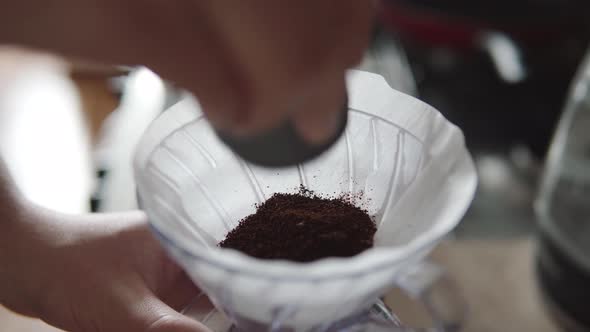 Barista Pouring Ground Beans From a Grinder Into a Paper Filter V60