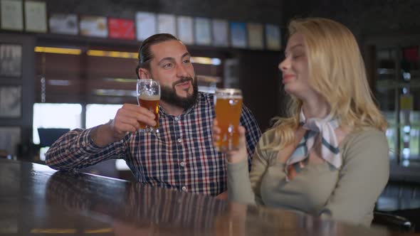 Portrait of Happy Loving Man Toasting Clinking Glasses with Woman Drinking Beer in Slow Motion alt