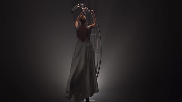 Gymnast in Dress Rotates on a Metal Construction in the Form of a Month. Smoke Background alt