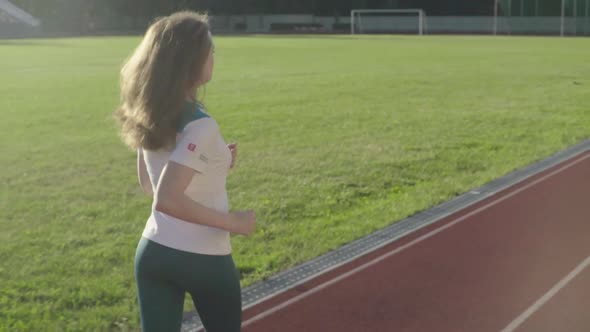 Athletic Young Girl Runs in the Stadium. Slow Motion alt