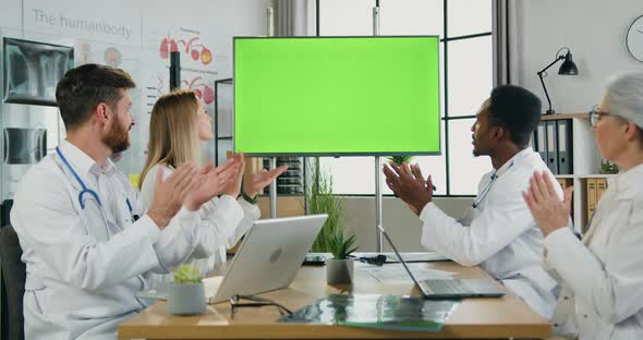 Team of Doctors Sitting in front of Green Chroma Key Screen and Clapping Hands alt
