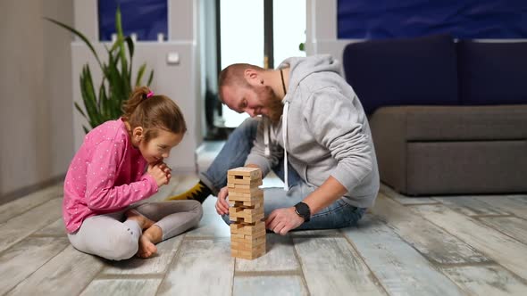 Happy Handsome Father and Happy Daughter Play Game with Wooden Tower Blocks Bricks alt