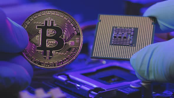 Closeup of Businessman Hands Hold Gold Bitcoin and CPU on Motherboard Background