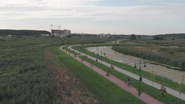 Woman on retro bike rides on cycle path on promenade in summer. Cyclist happy girl is on bicycle alt