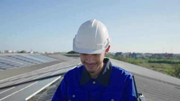 Asian technician inspection solar cell panels field of on roof top factory.
