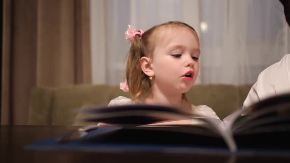 A Little Girl Sits in a Cafe and Flips Through the Pages of the Menu alt