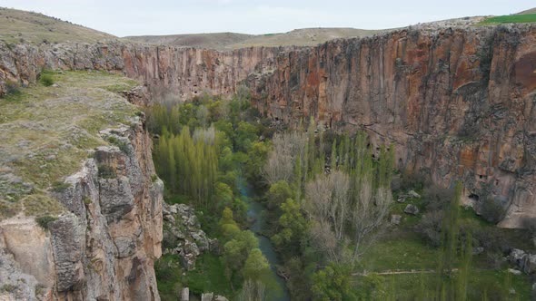 Aerial drone shot over river passing through Ihlara Canyon in Cappadocia, Turkey on a cloudy day. alt