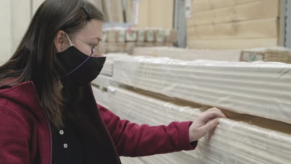 Woman in Building Materials Store Chooses Long Wooden Slats to Buy