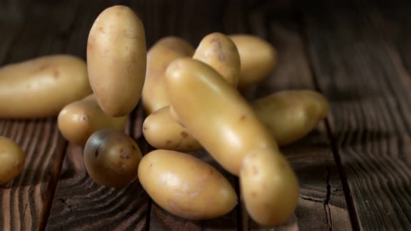 Super Slow Motion Shot of Potatoes Rolling on Old Wooden Table at 1000Fps. alt