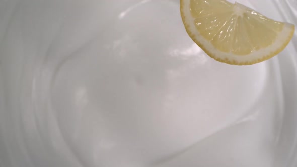 A sliced lemon falls onto yogurt and lemon rain follow - High-angle shot