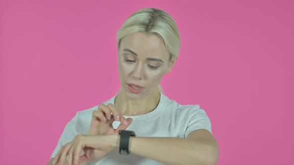 Young Woman Browsing Application on Smartwatch, Pink Background alt