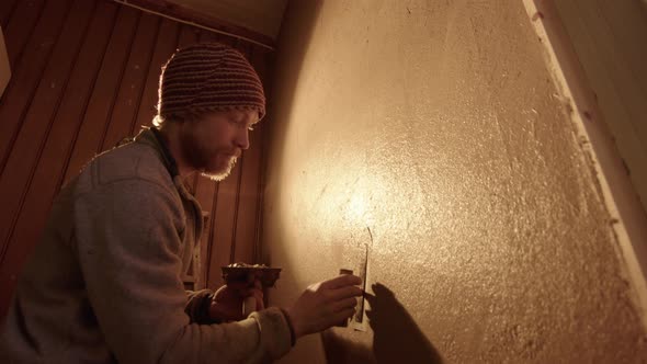 WIDE LOW ANGLE - A handsome professional plasterer using a Japanese trowel alt