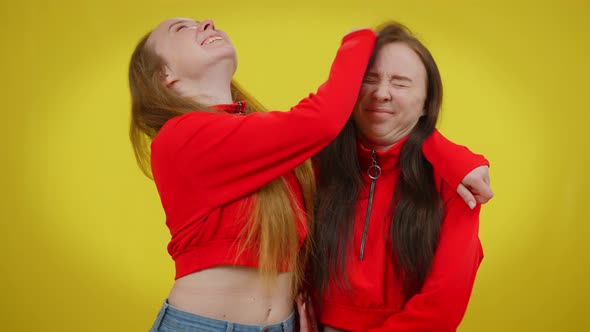 Joyful Young Twin Sisters Having Fun at Yellow Background Laughing alt