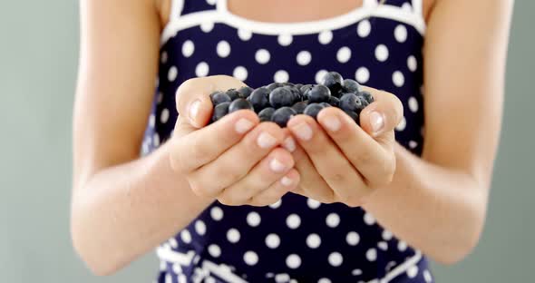 Close-up of woman holding blueberry alt