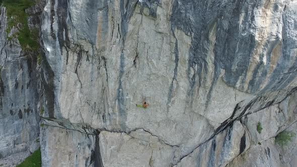 Aerial drone view of a man rock climbing up a mountain. alt