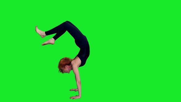 Slim Woman Standing on Hands During Yoga Practice Against Green Screen
