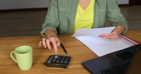 Woman accountant sit calculate expenses on calculator at wooden table, modern workplace alt