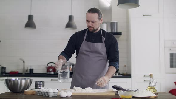 Young Handsome Male Chef Preparing Dough at Home in the Kitchen alt