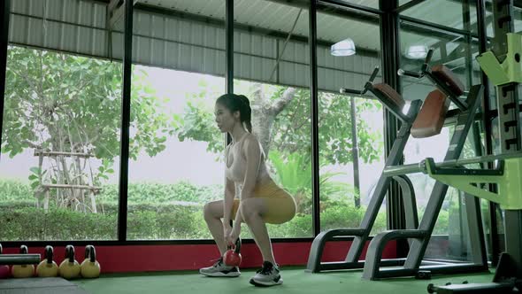 beautiful Asian woman is lifting a steel ball in the gym to strengthen her muscle mass.