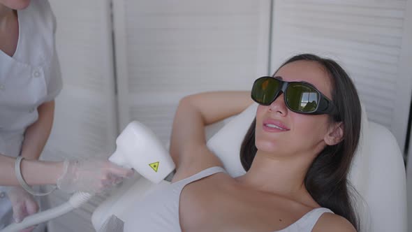 Beautician Doing Armpit Laser Hair Removal of Attractive Sexy Woman Lying on Medical Couch and alt