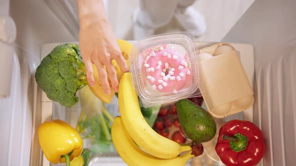 Woman unpacking fresh food, vegetable and fruit into refrigerated.