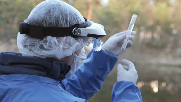 A biologist takes water samples from the river for laboratory research. alt