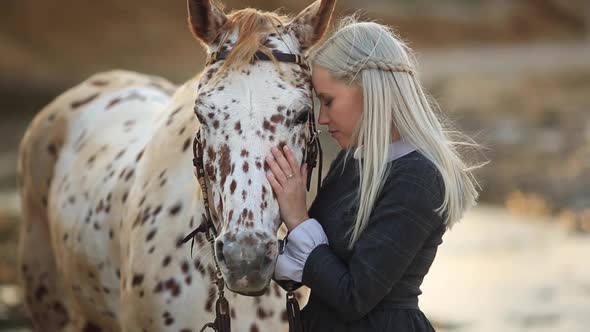 Young Blonde Girl Stroking a Brown Horse
