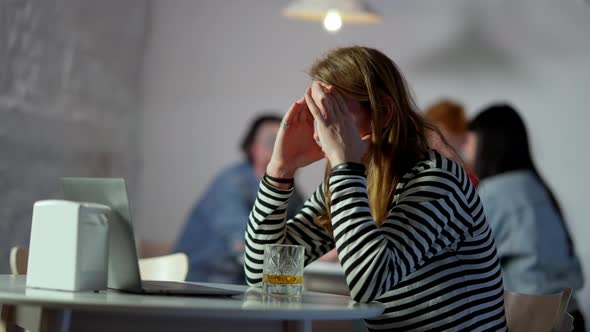 Nervous Young Man Messaging Online on Laptop and Drinking Whiskey in Slow Motion alt