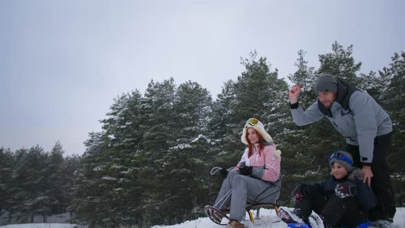 Winter Activities Happy Parents with Children Have Fun Sledding Down the Slope in the Forest in