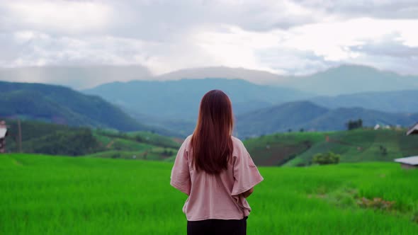 Young woman traveler on vacation enjoying and looking at beautiful green rice terraces field alt