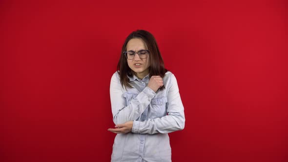A Young Woman with Glasses Has a Sore Elbow and Holds It in Her Hand alt