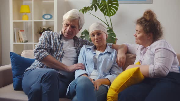 Senior Cancer Woman with Headscarf Sitting on Couch with Husband and Daughter alt