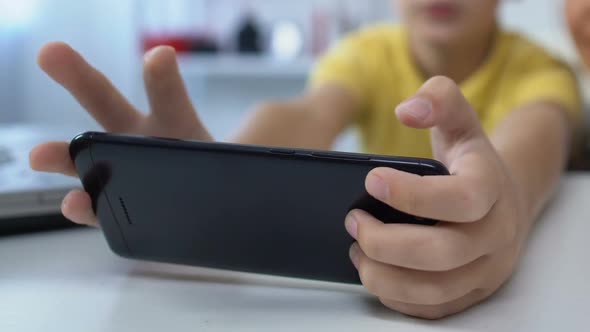 Young Mother Supporting Small Son During Video Game Playing on Smartphone