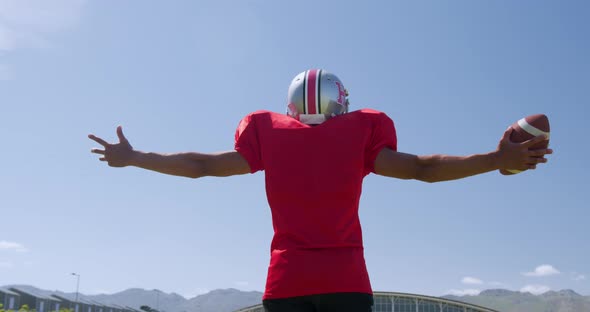 American football player standing with arms raised alt