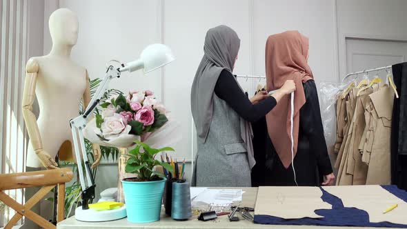 Woman muslim designer measuring back of customer inside a tailor shop