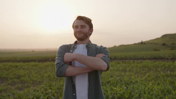 Close Up View of a Young Man and Smiles and Crosses His Hands alt