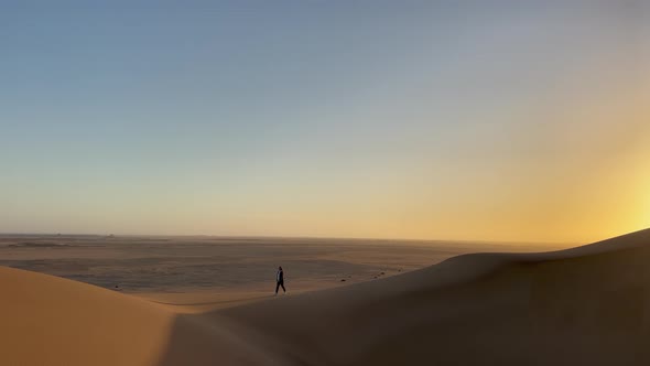 A Young Woman Walks Along Sandy Dunes in Namibia