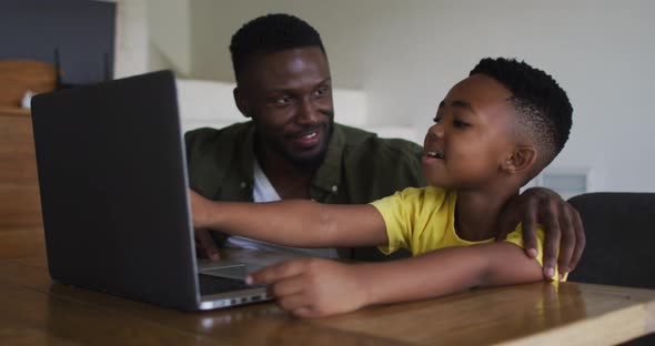 African american father and son using a laptop together alt